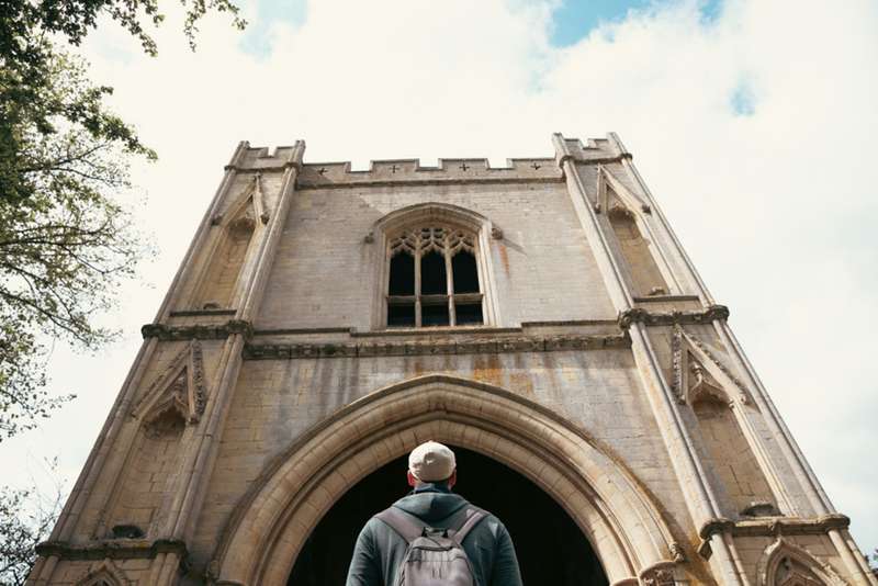 Man looking up at a church bell tower