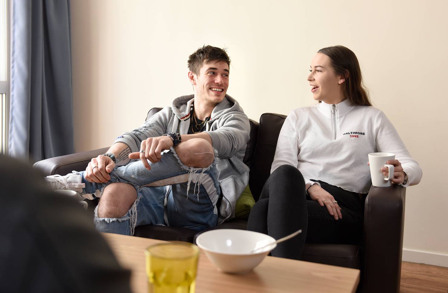Two students sitting and talking on a sofa