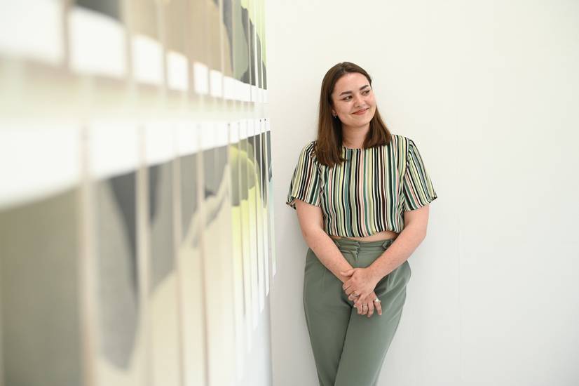 A student standing next to their artwork