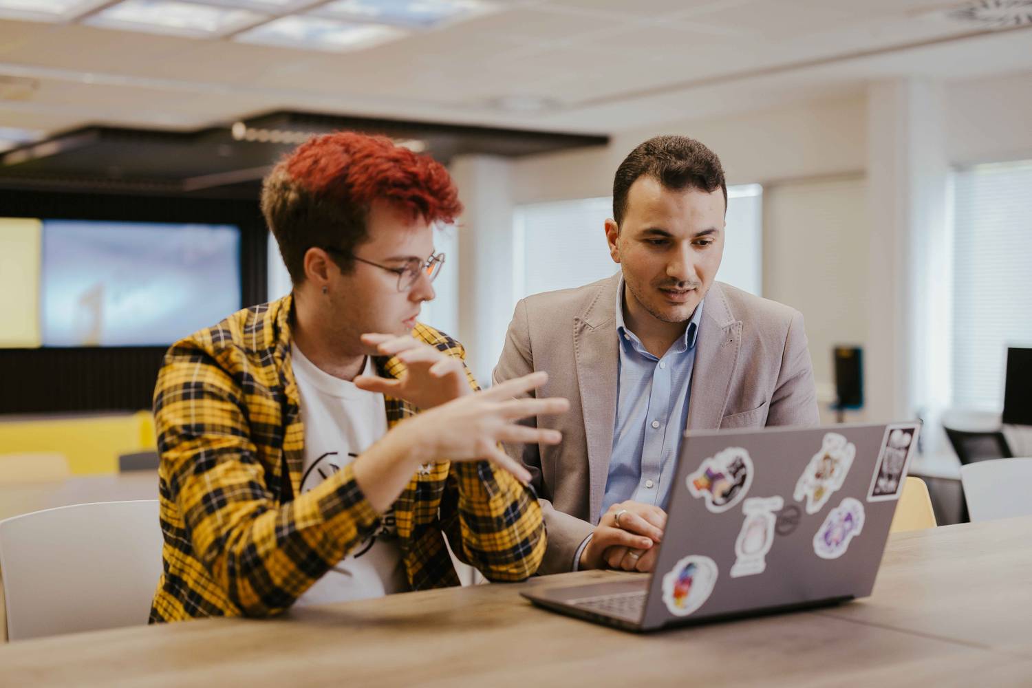 A computing student and lecturer discussing something on a laptop