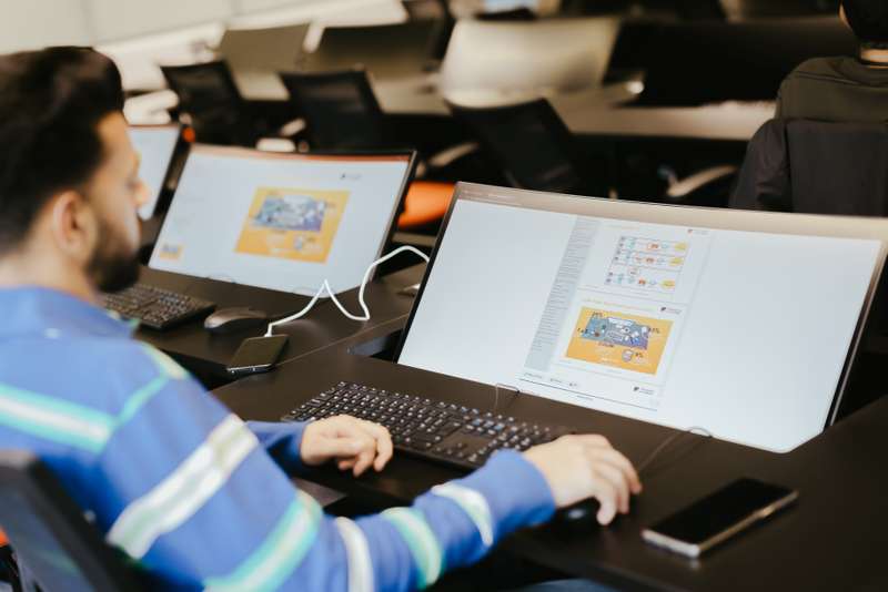 Student sitting at a computer screen and black desk