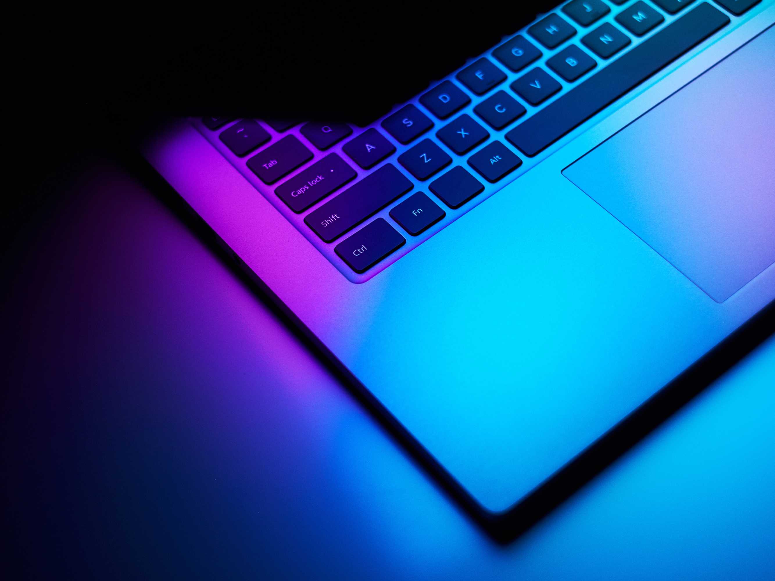 Close up image of laptop in dark neon light.
