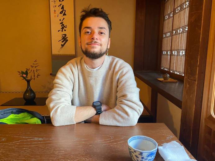 A student wearing a beige jumper sitting at a table