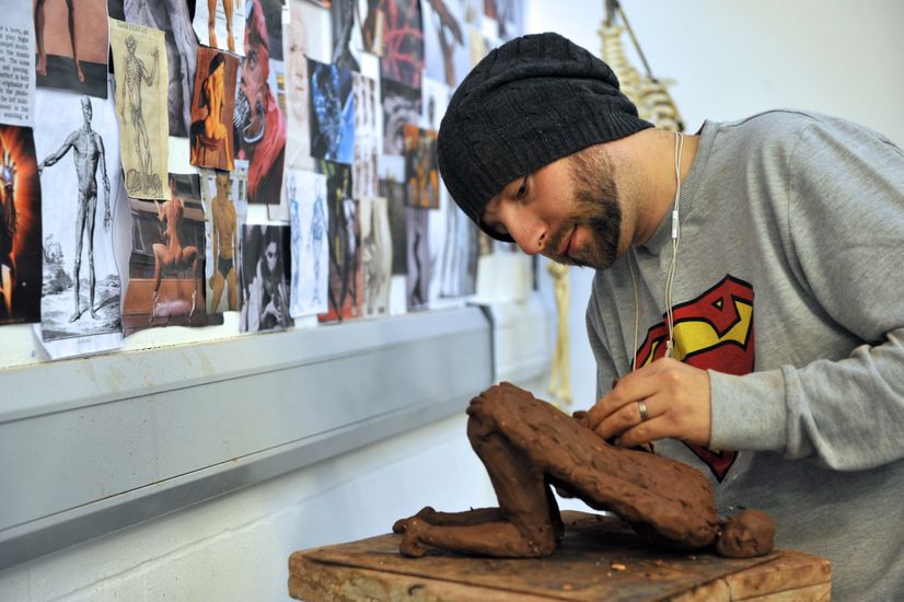 A student standing and sculpting the human form from clay