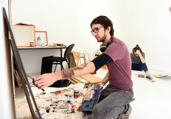 A student sitting on the floor painting