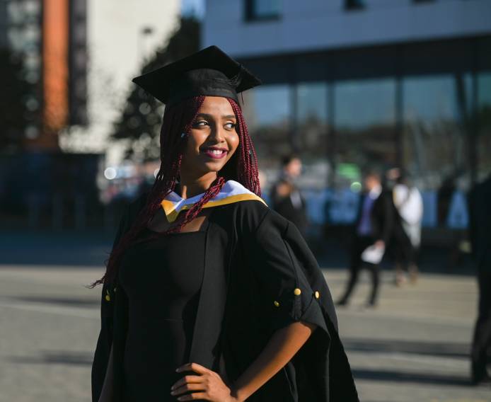 A student standing in their cap and gown