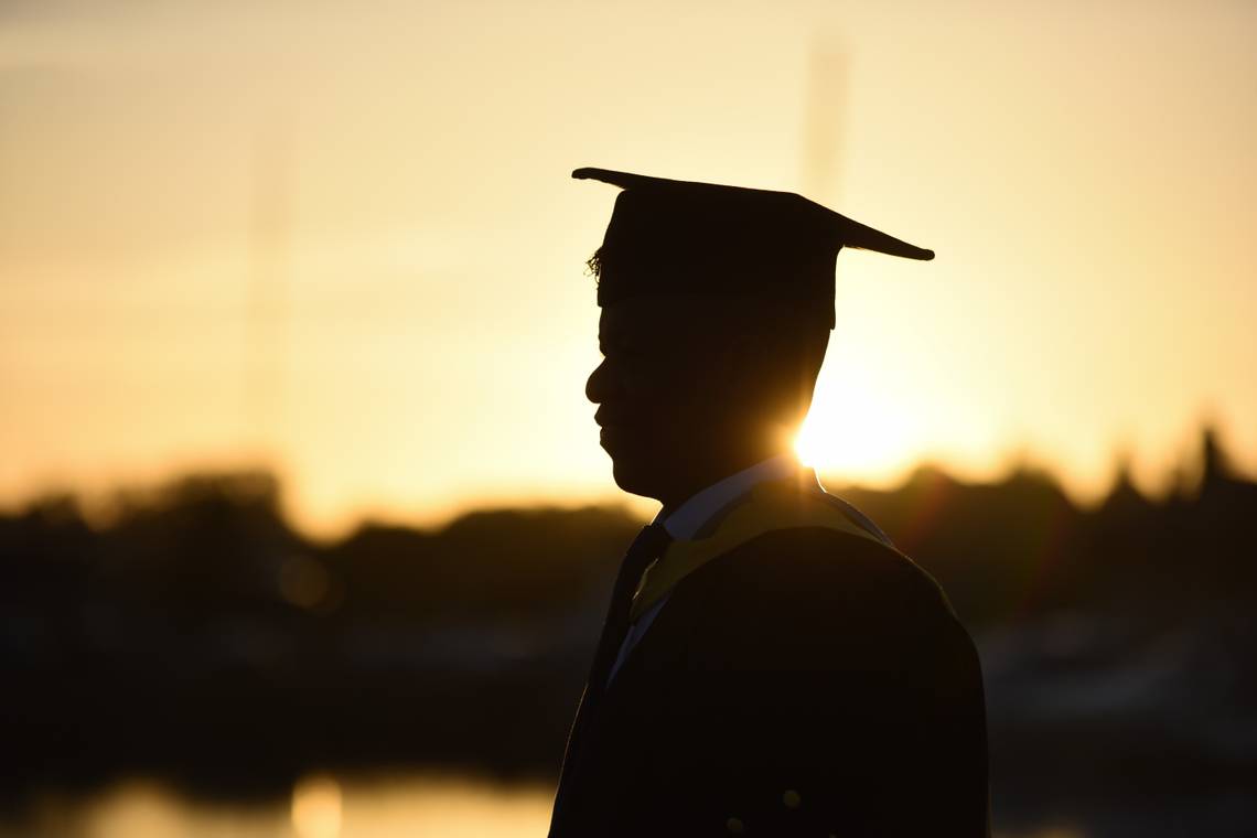 A silhouette of a student in their cap and gown