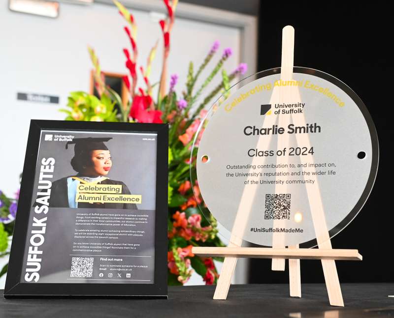 Display at University of Suffolk event featuring an award titled 'Celebrating Alumni Excellence' for Charlie Smith, Class of 2024.