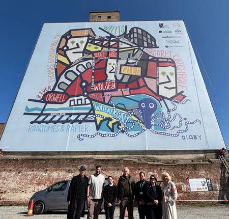 The Ipswich map artwork mural on the side of the Paul's silo building on Ipswich Waterfront. A group of those involved stand in front of the new artwork