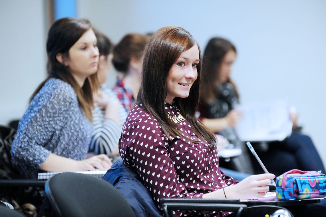 A student sitting in a lecture writing