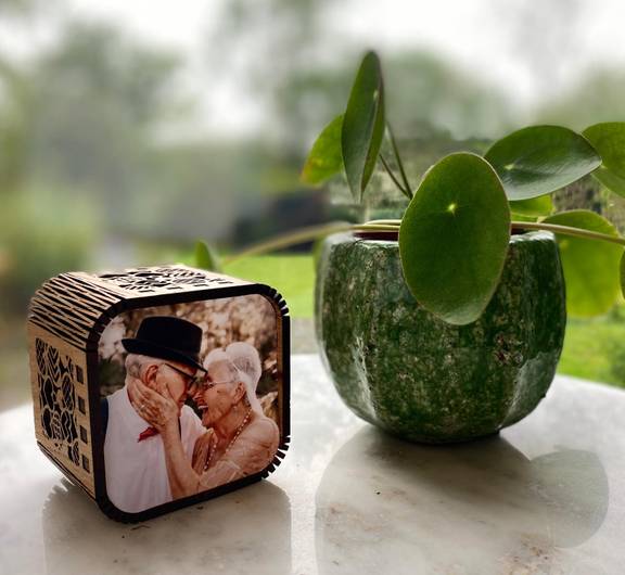A Chronicle memory box featuring a photograph of an older couple on the front. The box is sitting beside a pot plant