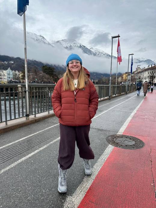A graduate outside wearing a blue hat and red jacket