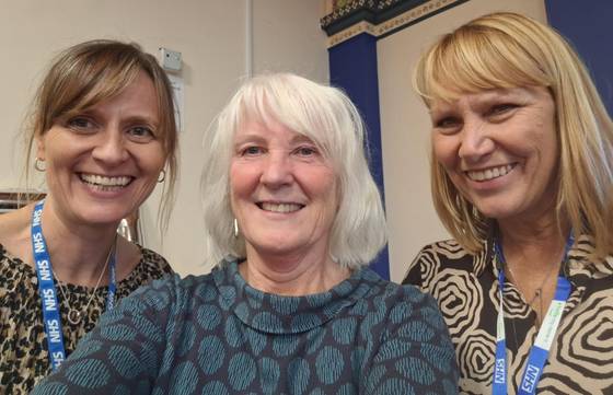 Three women together smiling after award win for one of them
