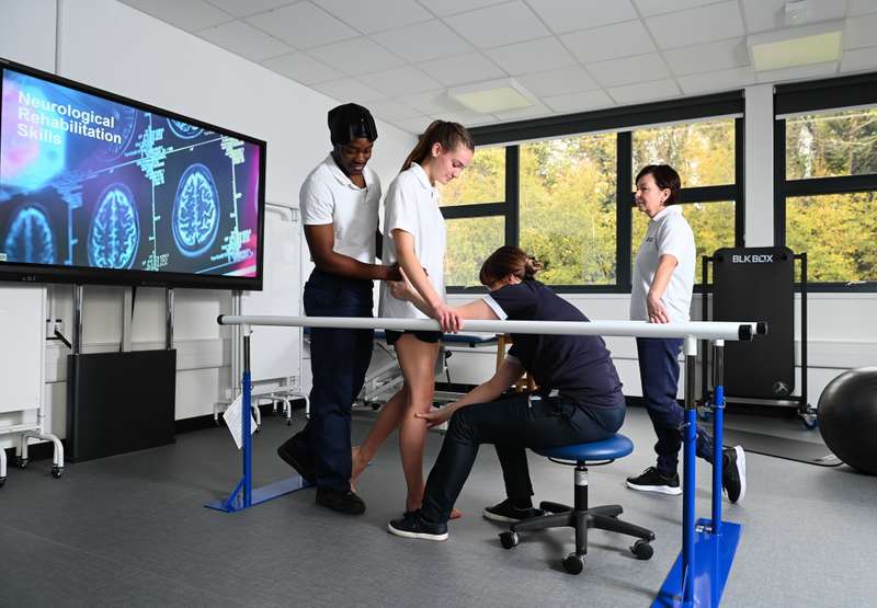 Students and lecturer using parallel bars