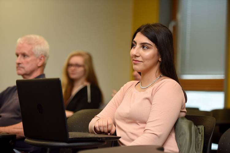A student sitting with a laptop in a seminar