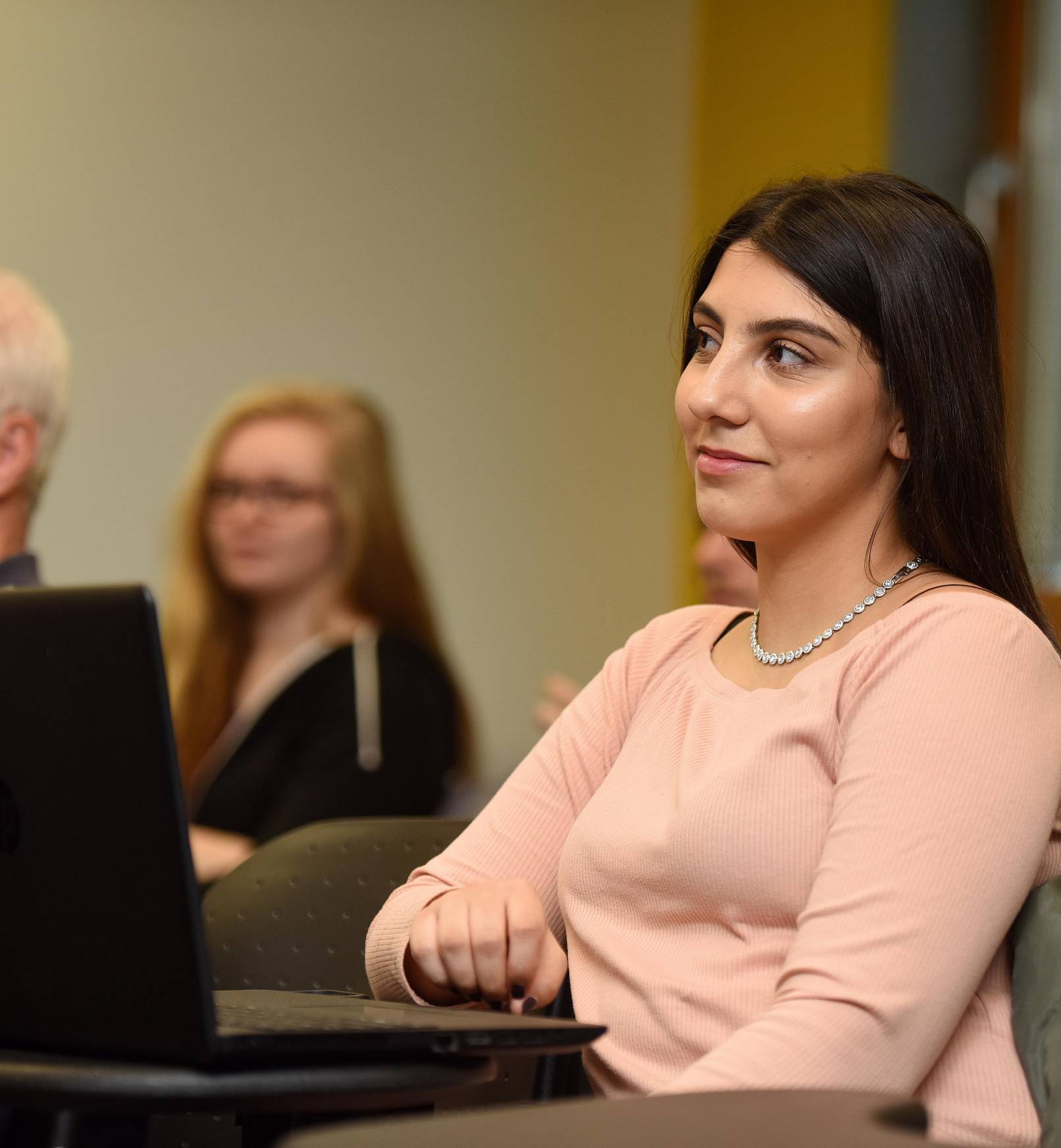 A student sitting with a laptop in a seminar
