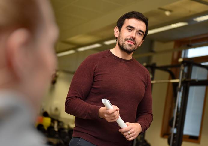 A lecturer holding a rolled up piece of paper