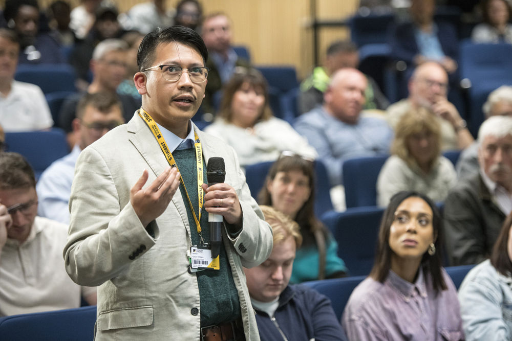 An audience member at the Spotlight Sufolk event holding a microphone and asking a question to the panel