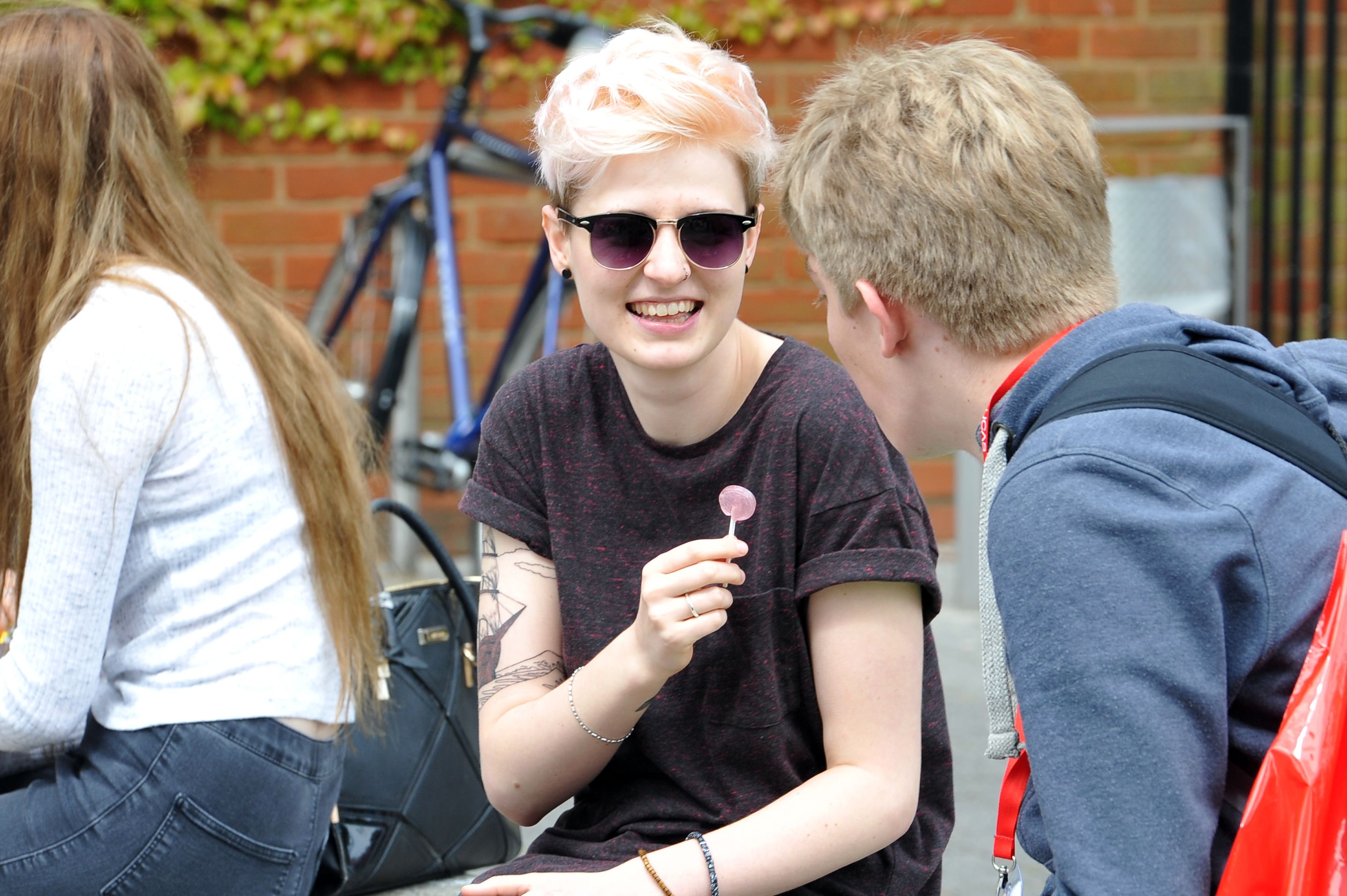 A student with a lollipop sitting on the plaza